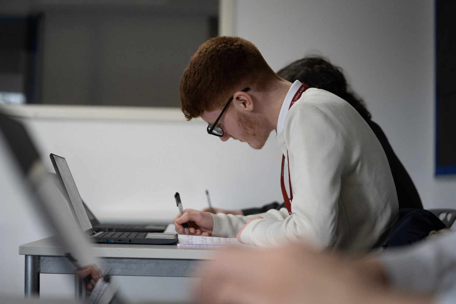 Post-16 students making notes during a lesson