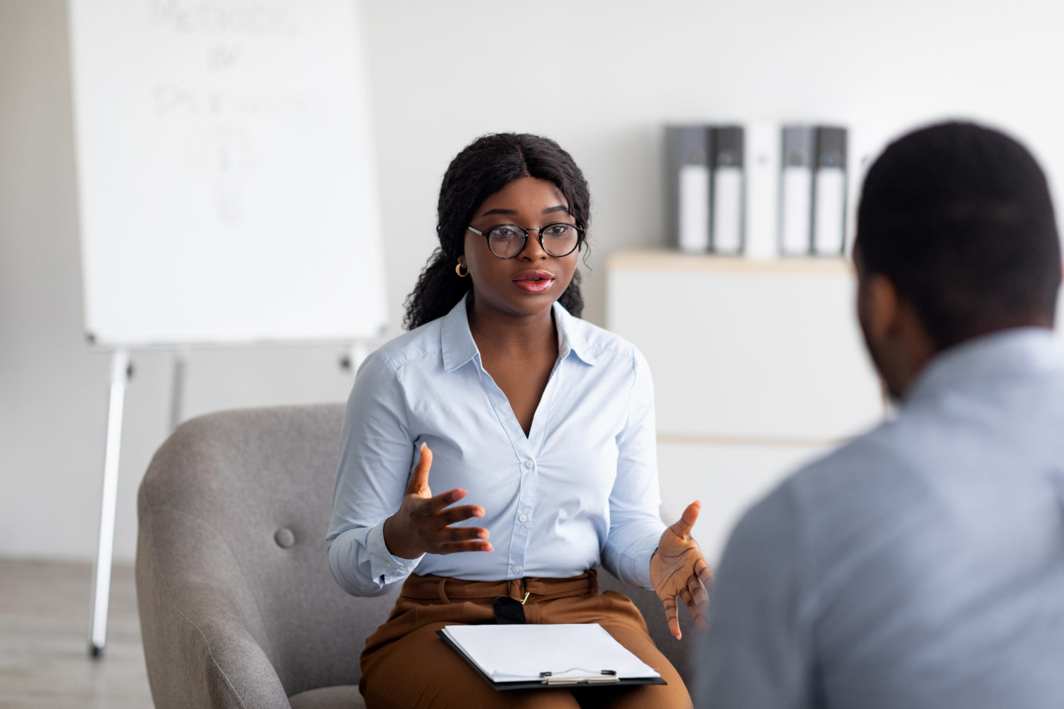 Psychological counselling. Professional female psychotherapist having session with young black guy at office. African American counselor giving advice to millennial man at mental health clinic