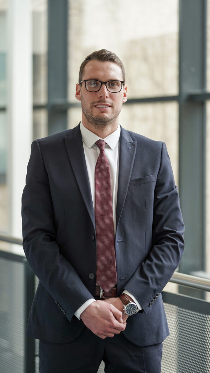 A picture of the principal standing in a well lit corridor