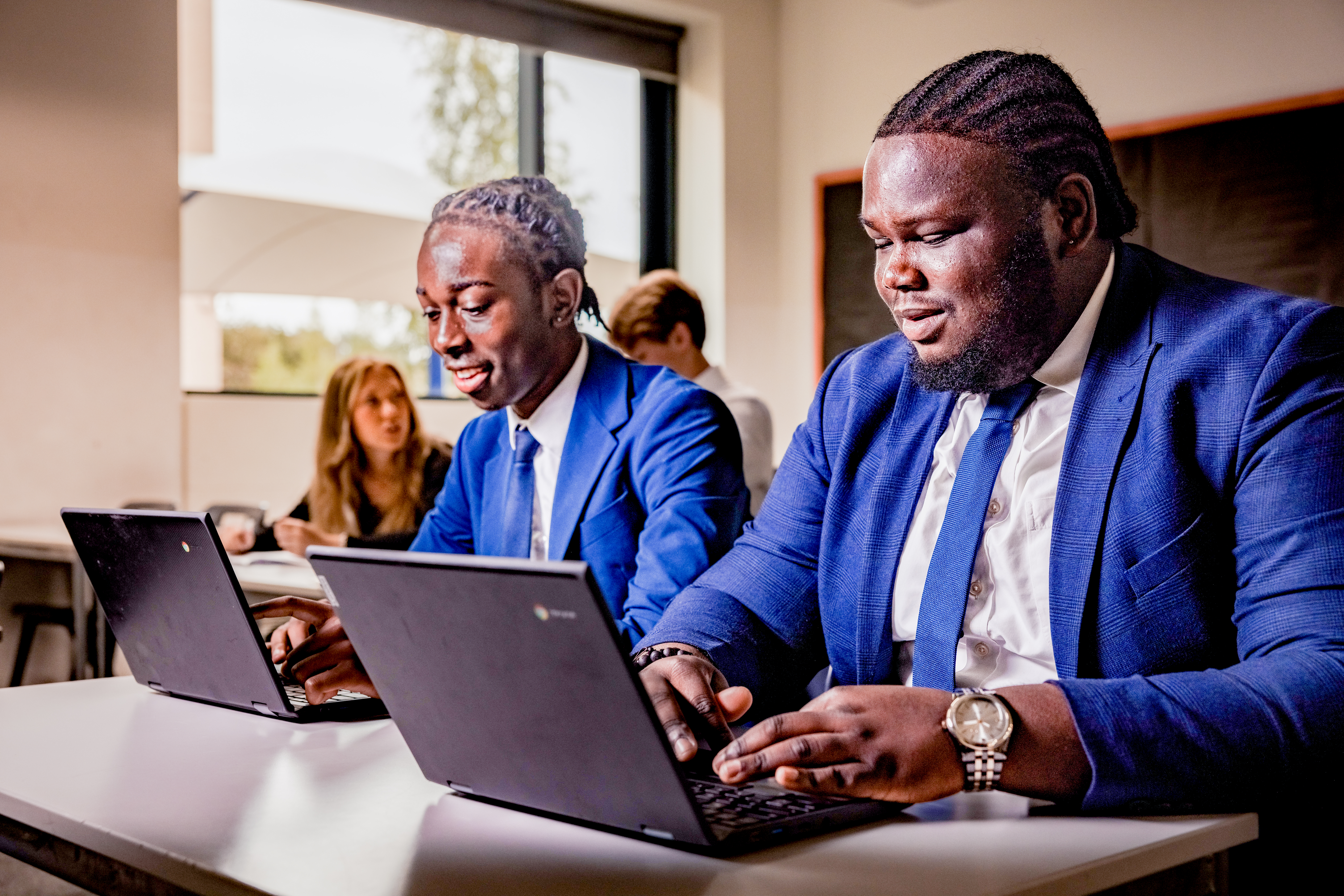 Two Sixth Form students using their Chromebooks in a classroom