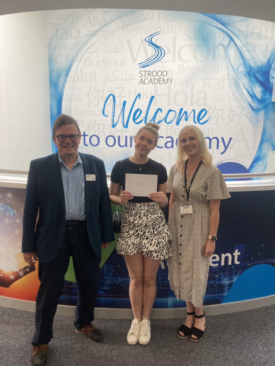 A female Post-16 student is pictured smiling for the camera alongside two members of staff, whilst holding her A-Level results in her hands.