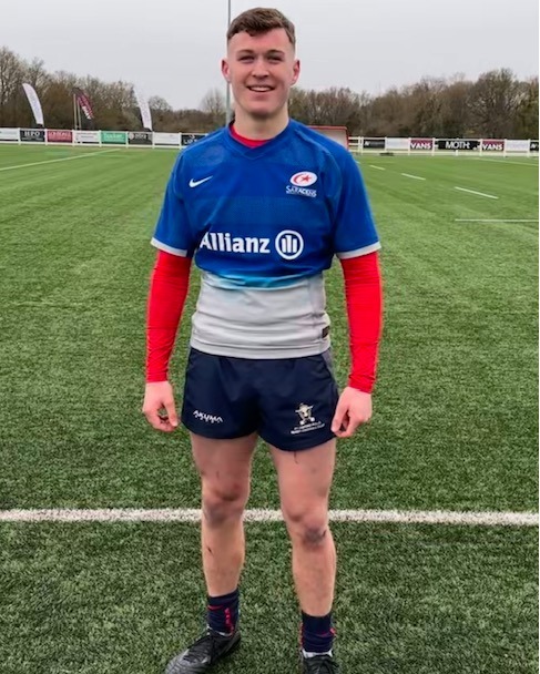 A student in a sports kit smiling