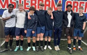 A team of boys wearing football kits smiling for a photo